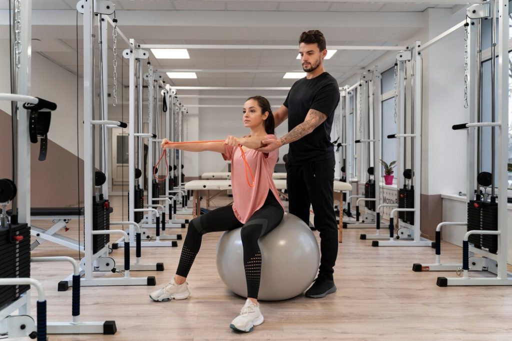 Personal trainer guiding client on stability ball exercise in Congleton gym