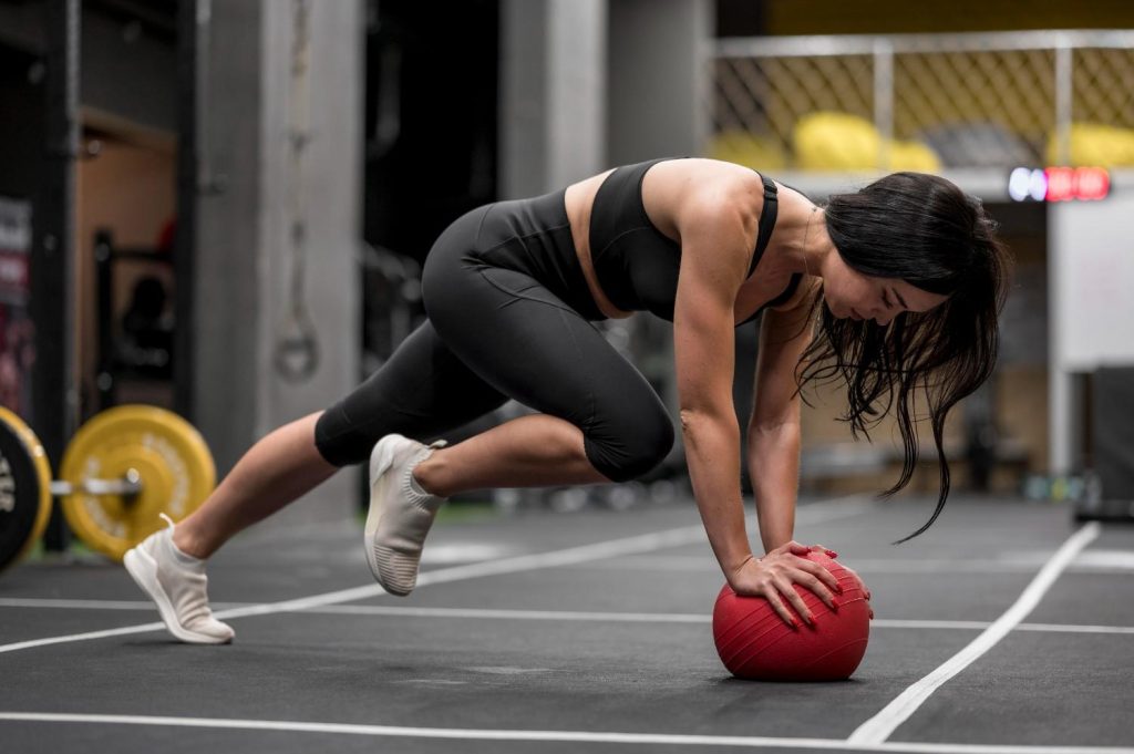 Woman performing functional training exercise in a UK gym with strength equipment