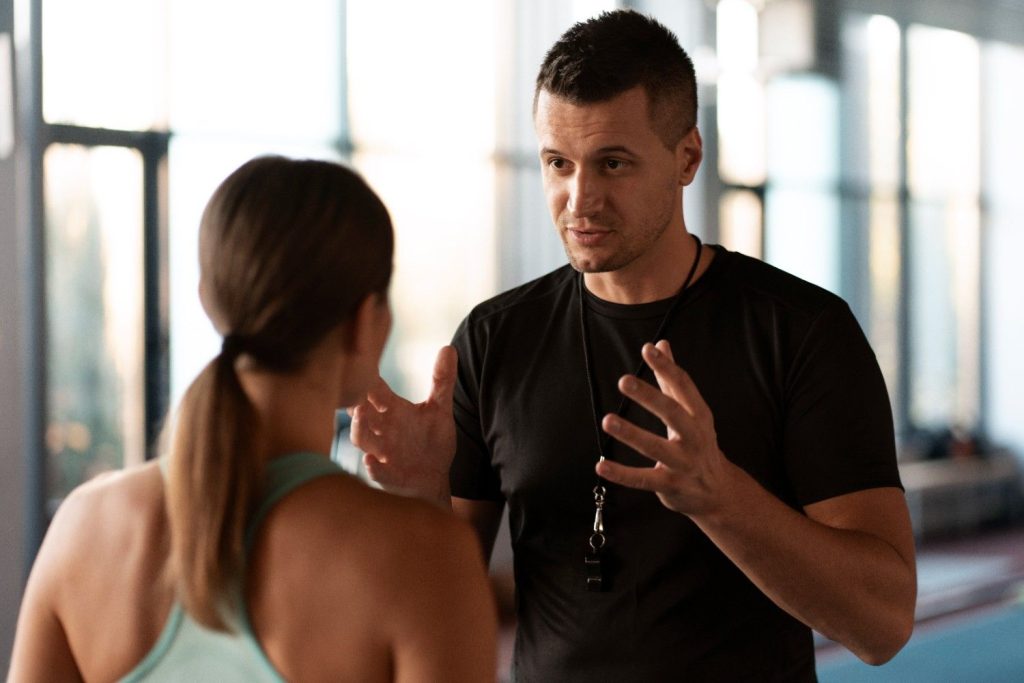 Personal trainer giving fitness advice to client in Congleton gym