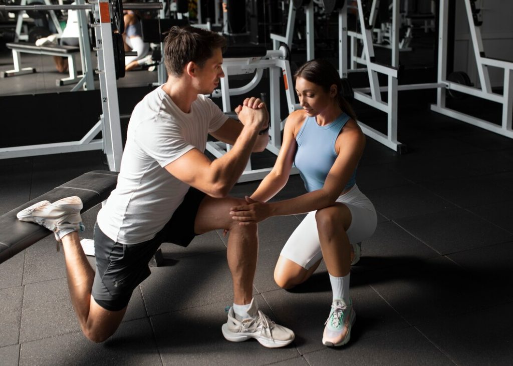 Personal trainer assisting client with knee support exercise in Congleton gym