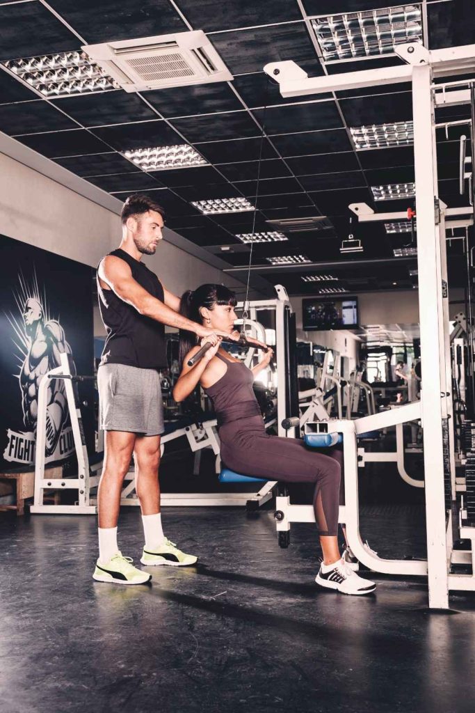 Personal trainer assisting lat pulldown exercise in Congleton gym