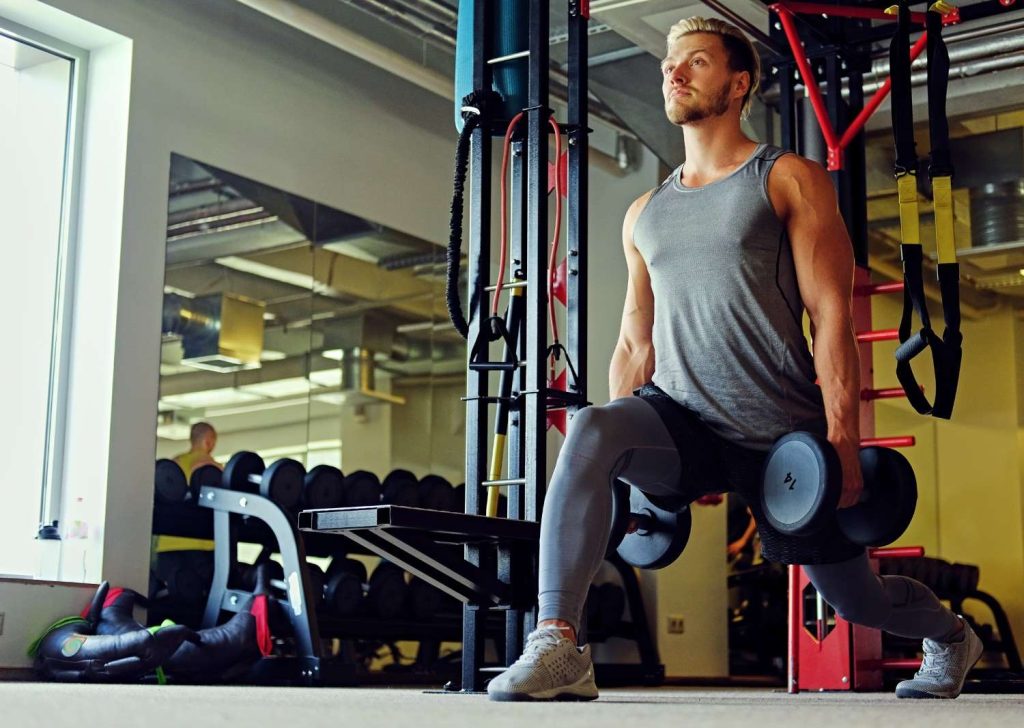 Man performing dumbbell lunges in Congleton gym for lower body strength