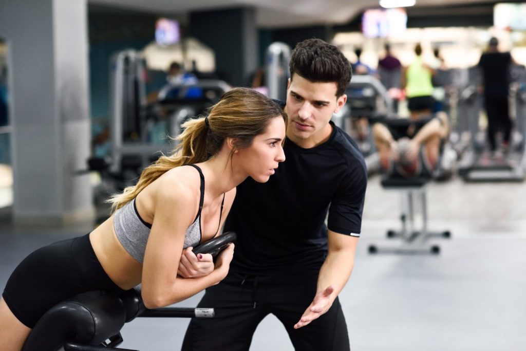 Personal trainer guiding client during strength exercise in Congleton gym