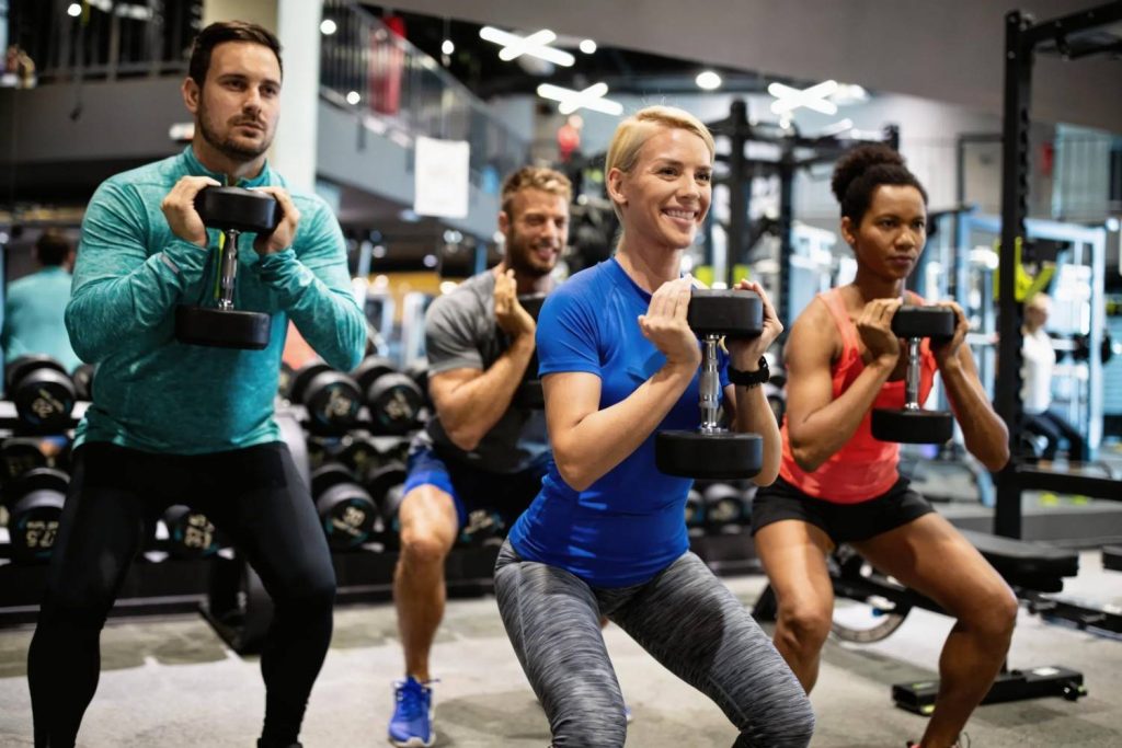 Group fitness class in Congleton gym doing dumbbell squat exercises